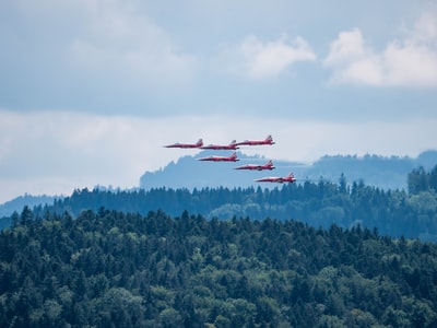 红白相间的飞机在青山上空飞舞